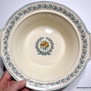 May include: Cream-colored ceramic serving bowl with a turquoise floral border and a central design of a basket of fruit. The bowl has a wide rim and two handles. The Etsy shop name "panchosporch.etsy.com" is visible in the bottom right corner.
