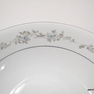 May include: A white ceramic bowl with a gray and blue floral design around the rim.
