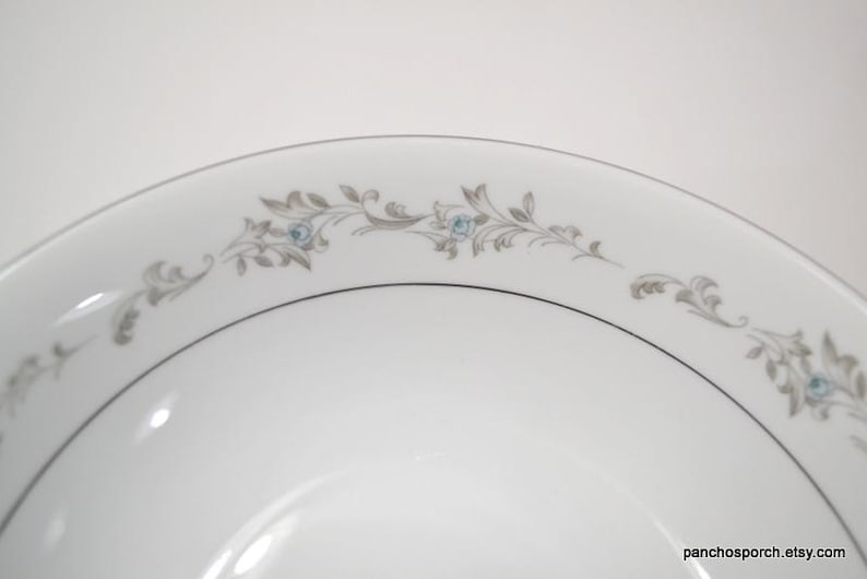 May include: A white ceramic bowl with a gray and blue floral design around the rim.