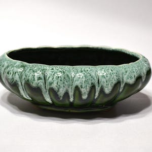 May include: An oval ceramic planter featuring a scalloped rim and a glossy glaze. The exterior displays a dark forest green base color with a white drip glaze effect cascading from the top edge, creating a textured, multi-tonal appearance.