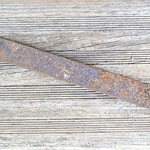 May include: A long, rectangular piece of rusted metal with a rounded end, lying on a weathered wooden surface. The metal has a textured, aged appearance, with shades of brown and orange. The website address "panchosporch.etsy.com" is visible.