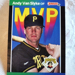 May include: A baseball card featuring Andy Van Slyke of the Pittsburgh Pirates. The card has a colorful background with the word "MVP" in large yellow letters. Van Slyke is wearing a Pirates uniform and holding a bat.