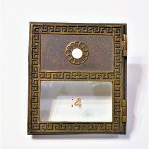 May include: A vintage brass mailbox with a glass window and a decorative keyhole. The mailbox has a Greek key design around the edges.