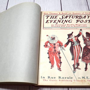 May include: An open vintage copy of The Saturday Evening Post magazine dated February 5, 1898. The cover features an illustration of three figures in theatrical costumes, including a clown, and the text In Rue Royale by M. E. M. Davis.