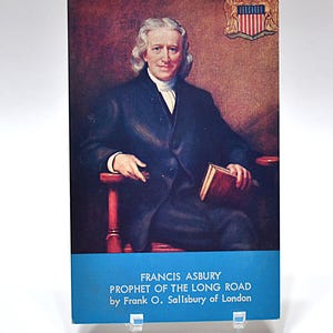 May include: A book cover displaying a portrait of Francis Asbury, with the title "The Prophet of the Long Road." The cover includes a blue banner with the author's name and publisher. The image is set against a neutral background.