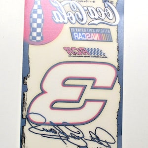 May include: A rectangular sticker featuring a Coca-Cola bottle, the number 3, and NASCAR branding. The number 3 is white with a pink and blue outline. The Coca-Cola logo is in white script. The sticker has a blue border and a signature.