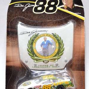 May include: Die-cast NASCAR race car, white with green and yellow accents, featuring the number 88 and UPS branding. The packaging includes a tribute to Arnold Palmer and the text "50 Years of Legendary Golf."