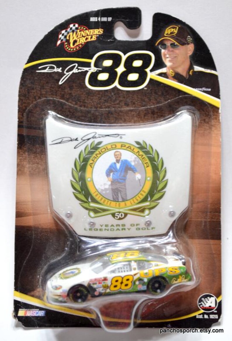 May include: Die-cast NASCAR race car, white with green and yellow accents, featuring the number 88 and UPS branding. The packaging includes a tribute to Arnold Palmer and the text "50 Years of Legendary Golf."