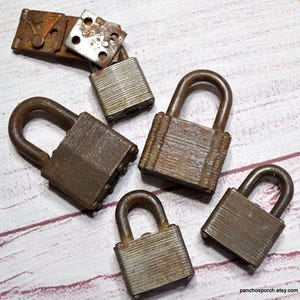 May include: An assortment of vintage, rusty padlocks with arched handles and rectangular bodies. The locks vary in size and show signs of age and wear, with a weathered, metallic appearance. Some locks are open, and some are closed.
