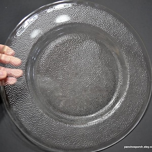 May include: A white ceramic mug with a black handle and the text "But First, Coffee" in a black, bold font. The mug is sitting on a white surface. The mug is approximately 4 inches tall.