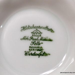 May include: Close-up of a white porcelain dish with green text and a crown logo. The text reads "Hutschenreuther Abt. Paul M&uuml;ller Selb Bavaria Germany Werdenfels."