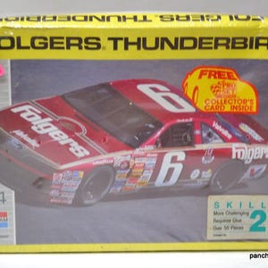 Puede incluir: Un kit de modelo de coche Folgers Thunderbird en una caja amarilla y gris. El coche de carreras rojo tiene el n&uacute;mero 6 y la marca Folgers. La caja incluye una pegatina "Tarjeta de coleccionista GRATIS en el interior" y el logotipo de Monogram.