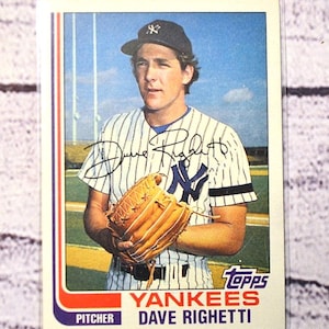 May include: A vintage Topps baseball card featuring Dave Righetti, a New York Yankees pitcher. The card shows a player in a pinstriped uniform and a dark cap, holding a tan leather baseball glove. The card includes a black ink signature across the chest.