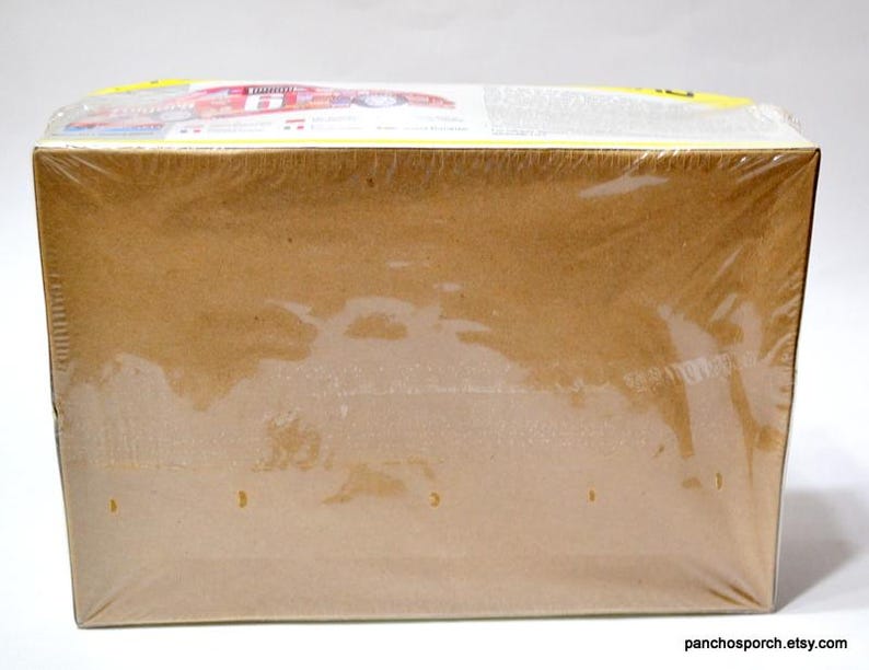 Puede incluir: Una caja rectangular de cart&oacute;n envuelta en pl&aacute;stico transparente. La caja es de color marr&oacute;n claro y parece estar sellada. La parte superior de la caja tiene texto y gr&aacute;ficos visibles.