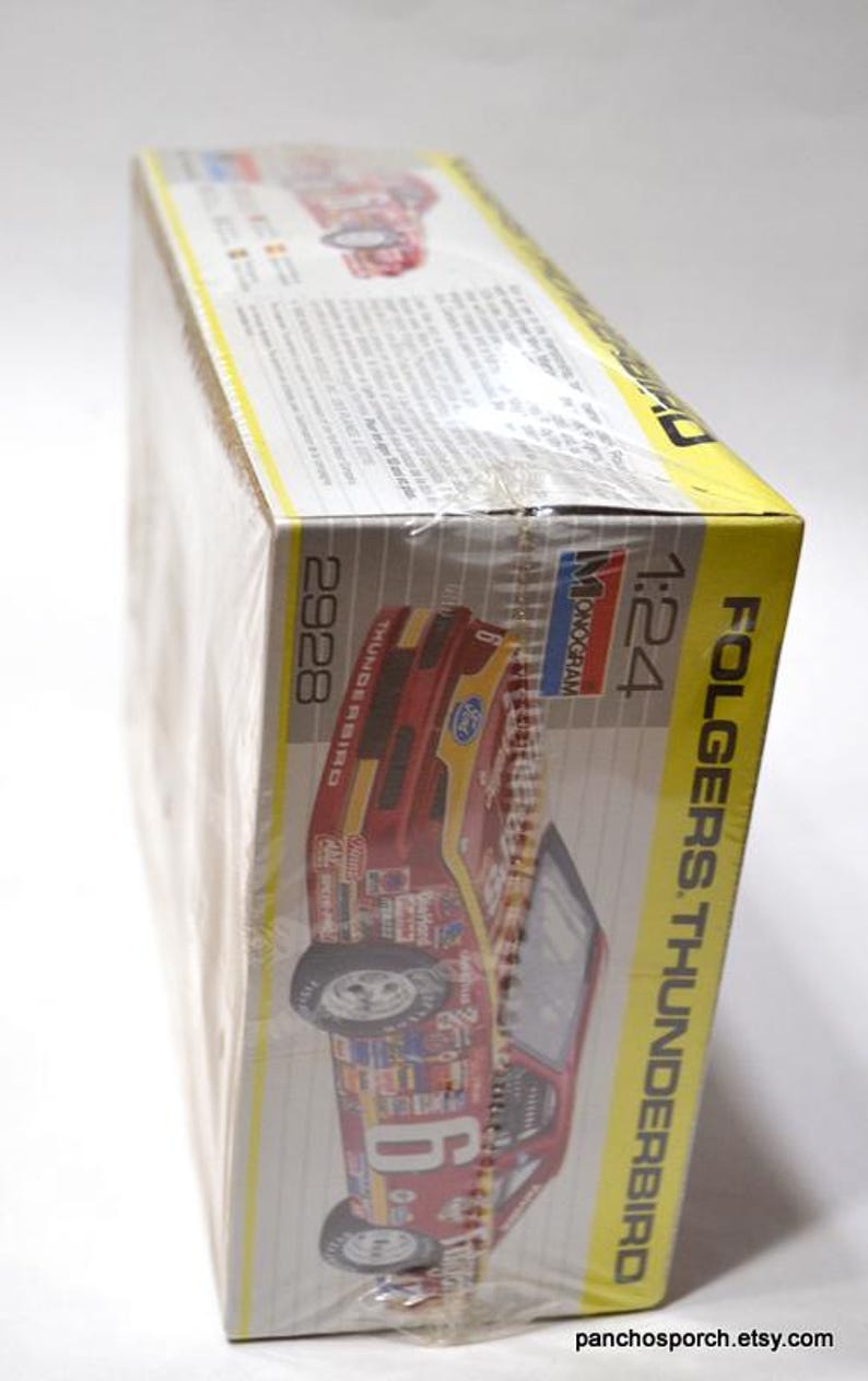 Puede incluir: Una caja de modelo de un coche de carreras Folgers Thunderbird. La caja es amarilla y blanca con una imagen de coche rojo y dorado. La caja est&aacute; envuelta en pl&aacute;stico transparente y tiene el n&uacute;mero 6.