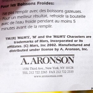 May include: Close-up of a white paper with text in English and French. The text includes instructions for cold beverages and trademark information for M&M'S characters. The A. Aronson logo is visible.