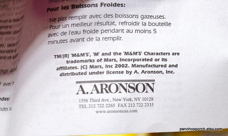 May include: Close-up of a white paper with text in English and French. The text includes instructions for cold beverages and trademark information for M&M'S characters. The A. Aronson logo is visible.