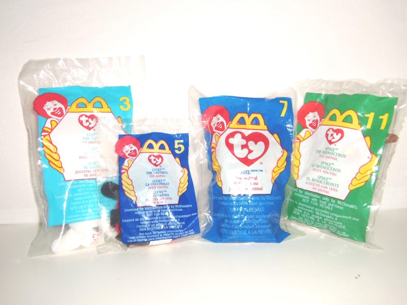 May include: Four Ty plush toys sealed in individual clear plastic McDonald's promotional bags. The bags are labeled with numbers 3, 5, 7, and 11, featuring the McDonald's logo, the Ty heart-shaped logo, and text in English, French, and Spanish.