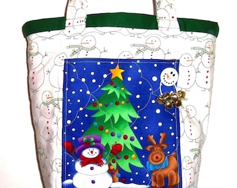 Könnte beinhalten: Eine gesteppte Tragetasche aus weißem Stoff mit Schneemannmuster und einem dunkelgrünen oberen Rand. Das mittlere Feld zeigt eine blaue Winterszene mit einem Weihnachtsbaum, einem Schneemann mit lila Hut, einem Rentier und goldenen Glöckchen.