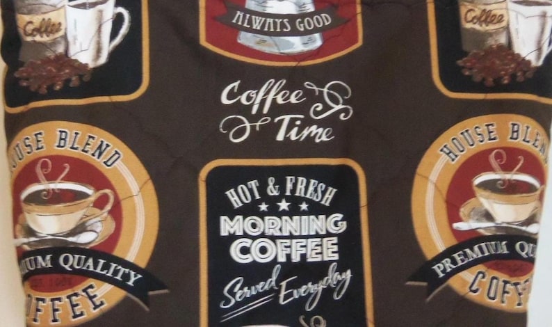 Puede incluir: Una tela de color marr&oacute;n oscuro con un patr&oacute;n repetitivo de tem&aacute;tica cafetera. El dise&ntilde;o incluye etiquetas circulares y rectangulares con textos como "House Blend", "Premium Quality Coffee", "Hot & Fresh Morning Coffee" y "Coffee Time".