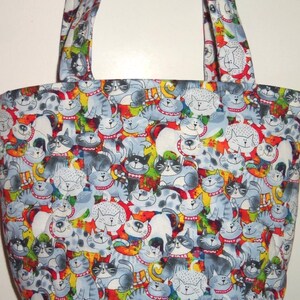 May include: A fabric tote bag featuring a repeating pattern of cartoon cats in shades of gray, white, and black. Each cat wears a red collar with white dots. The background is a vibrant mix of red, yellow, green, and blue abstract shapes.