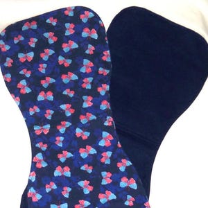 May include: Two blue fabric squares, one with a pattern of pink and blue butterflies on a dark blue background, and the other plain.