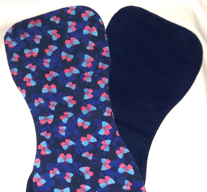 May include: Two blue fabric squares, one with a pattern of pink and blue butterflies on a dark blue background, and the other plain.