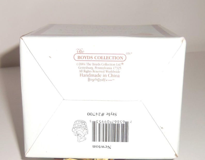 Op de afbeelding: Een witte doos met de tekst "The Boyds Collection" en "Newton". De doos bevat ook het stijlnummer #24700 en een barcode. Gemaakt in China.