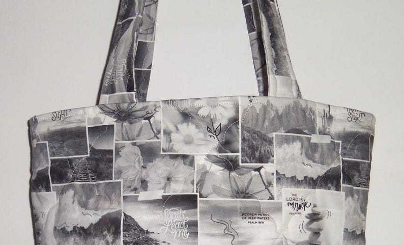 May include: A tote bag with a patchwork design in black and white. The bag features a variety of images, including flowers, landscapes, and text. The handles are made of the same fabric. The text includes the words "Sight", "Spirit Lead Me", and "The Lord is my Rock".