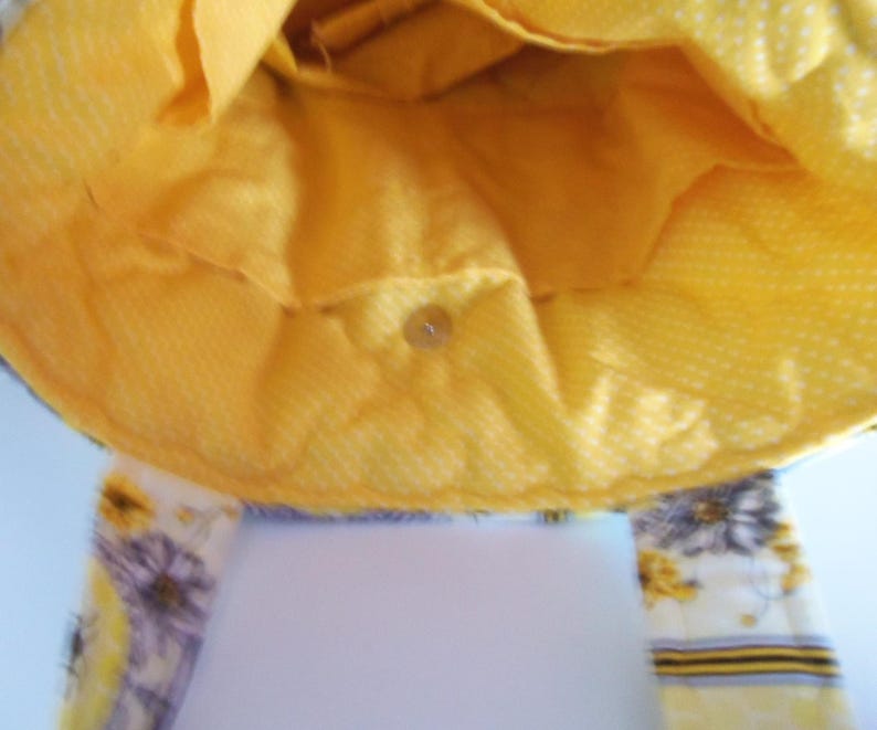 May include: A handmade yellow tote bag with a floral strap. The interior is a solid yellow, and the exterior features a yellow and white polka dot pattern. The strap has a floral design with yellow and purple flowers.