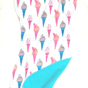 Op de afbeelding: Een baby-uitscheurdoek met een patroon van ijsjes in roze, oranje, blauw en bruin op een witte achtergrond. De achterkant is effen turquoise.