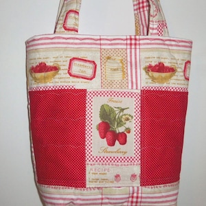 May include: A quilted tote bag featuring a patchwork design with red and beige stripes, polka dots, and strawberry-themed graphics. The centre panel displays a botanical illustration of strawberries with the text Fraise and Strawberry.