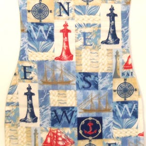 May include: A nautical-themed fabric with a repeating pattern of compasses, sailboats, anchors, and lighthouses in red, blue, and beige. The fabric is cut into a curved shape, possibly for a decorative item.