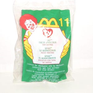 May include: A sealed clear plastic bag containing a McDonald's Ty toy. The green packaging features Ronald McDonald, the number 11, and the Ty logo. Text includes Spike the Rhinoceros Toy Animal, Le Rhinoc&eacute;ros Petit Toutou, and El Rinoceronte.