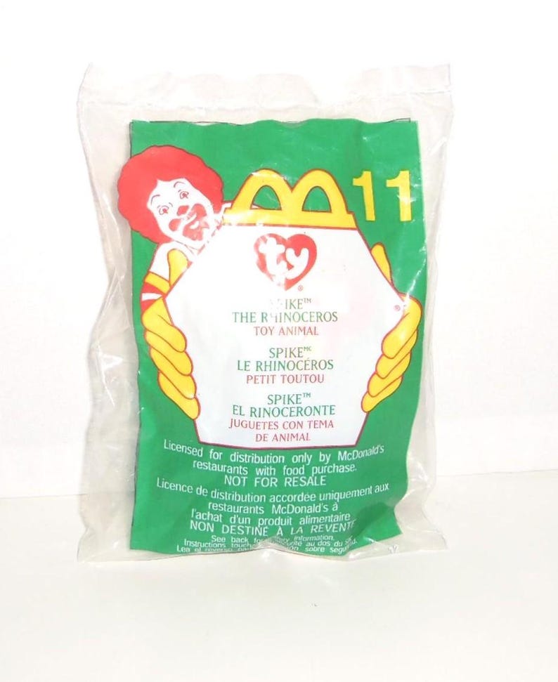 May include: A sealed clear plastic bag containing a McDonald's Ty toy. The green packaging features Ronald McDonald, the number 11, and the Ty logo. Text includes Spike the Rhinoceros Toy Animal, Le Rhinoc&eacute;ros Petit Toutou, and El Rinoceronte.