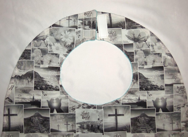 May include: A circular fabric tree skirt featuring a black and white collage print of religious imagery, including crosses, lighthouses, and hands, with the text "Walk by Faith not by Sight" and "Light of the World". It has a central opening and velcro.
