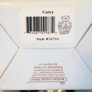 May include: A white box with a label that reads "Carey" above a barcode and a small illustration of a teddy bear in a basket. The style number is #24711. The box is from The Boyds Collection.