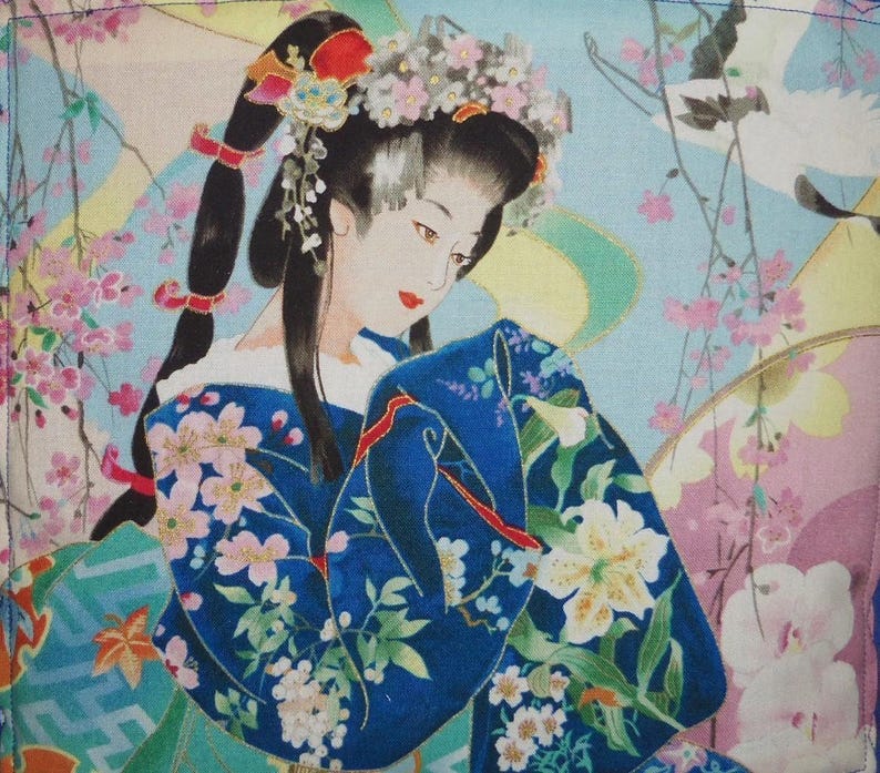 May include: A fabric print featuring a person with dark hair styled in a high ponytail with floral accessories, wearing a deep blue kimono adorned with white and pink floral patterns, set against a light blue background with cherry blossoms.