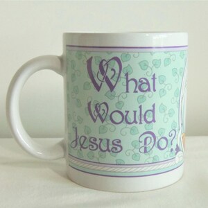 May include: A white ceramic mug featuring a light green background with a repeating pattern of small leaves. The text "What Would Jesus Do?" is printed in purple script lettering on the front, framed by thin purple and white border lines.