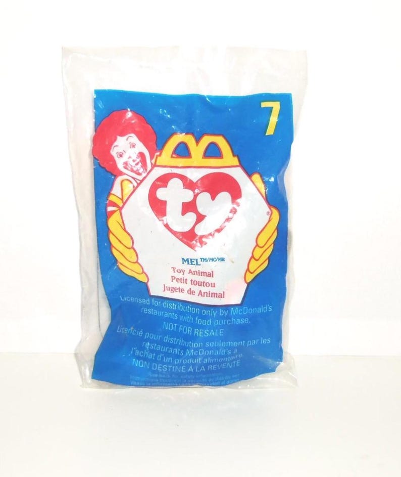 May include: A sealed clear plastic McDonald's Happy Meal toy bag featuring a blue background, the number 7, a graphic of Ronald McDonald, and a white heart-shaped Ty logo. The text reads Mel, Toy Animal, and includes licensing information.