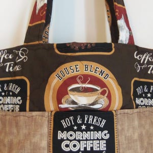 Puede incluir: Un bolso tote acolchado con un estampado de caf&eacute; en tonos marr&oacute;n y negro. La tela muestra textos como "Coffee Time", "House Blend" y "Hot & Fresh Morning Coffee" junto a ilustraciones de tazas de caf&eacute; con vapor sobre un fondo oscuro.