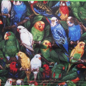 May include: A fabric panel featuring a dense, colorful pattern of various parrots and parakeets perched on branches amidst dark green foliage. The birds display vibrant plumage in shades of blue, green, yellow, red, and white. The design is framed by a solid bright green border.