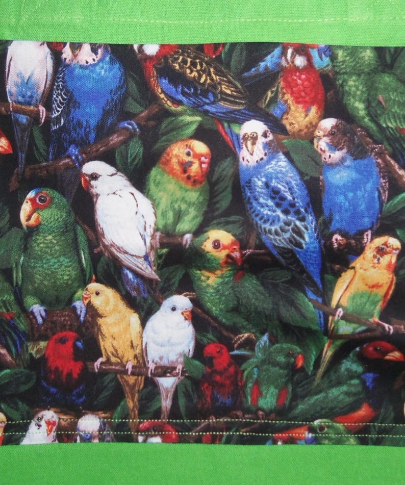May include: A fabric panel featuring a dense, colorful pattern of various parrots and parakeets perched on branches amidst dark green foliage. The birds display vibrant plumage in shades of blue, green, yellow, red, and white. The design is framed by a solid bright green border.