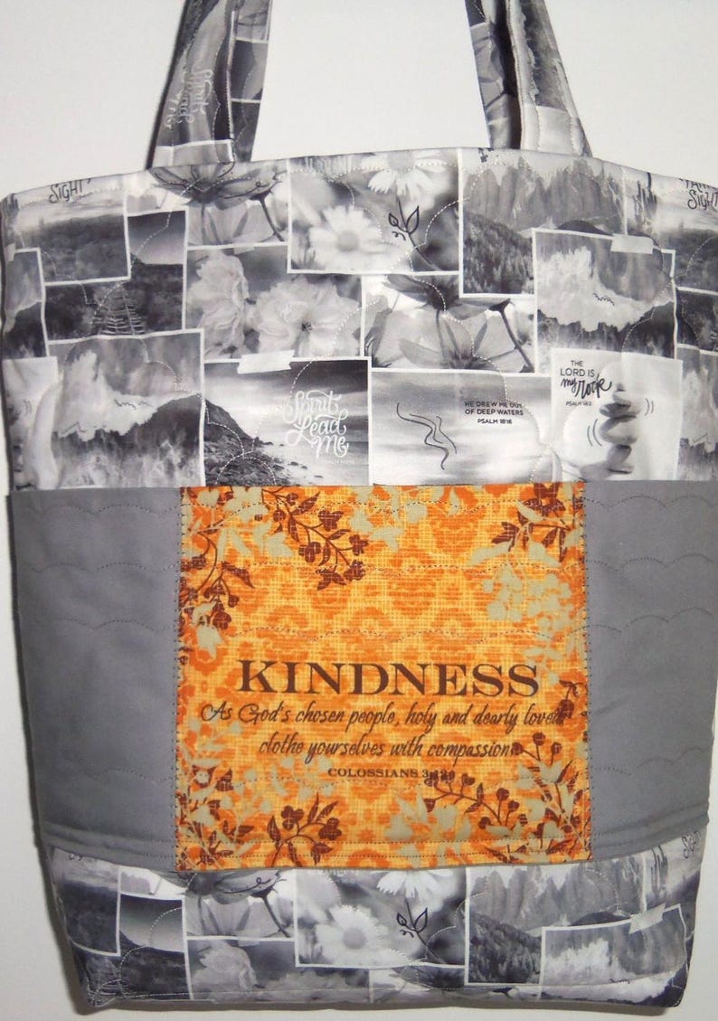 May include: A tote bag with a patchwork design. The top and bottom sections feature a collage of black and white images. The center has a gray panel with an orange floral design and the word "KINDNESS".