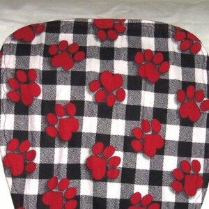 May include: A black and white checkered fabric with red paw prints. The fabric is soft and comfortable, perfect for making pet beds, blankets, or other crafts.
