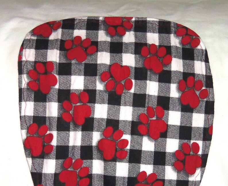 May include: A black and white checkered fabric with red paw prints. The fabric is soft and comfortable, perfect for making pet beds, blankets, or other crafts.