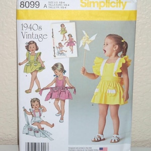 May include: A Simplicity sewing pattern envelope 8099 for 1940s vintage style children's clothing. The front displays illustrations and a photograph of a child wearing a yellow dress with ruffled straps and pockets, alongside a pinwheel.