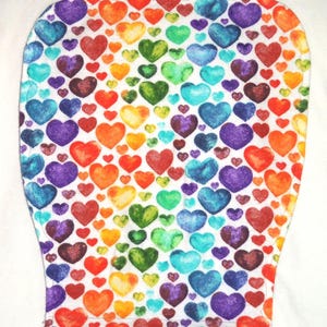 May include: A white fabric item covered in a pattern of colorful hearts in shades of red, orange, yellow, green, blue, and purple. The hearts are of varying sizes and are densely packed together.