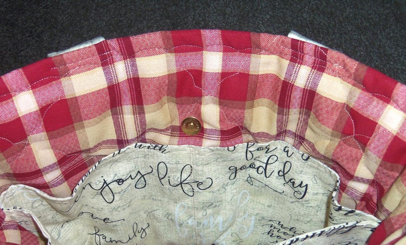 May include: A red and cream plaid fabric tote bag with a cream lining. The lining has the text "enjoy life with family for a good day" printed on it.