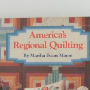 May include: A book titled America's Regional Quilting by Marsha Evans Moore. The cover features a colorful geometric quilt pattern in shades of red, orange, yellow, and blue, with the title printed in red text inside a light blue rectangular frame.